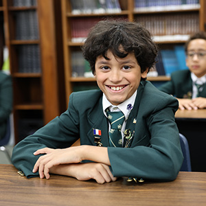 Boy smiling sitting at desk in classroom