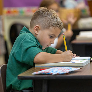 pencil-writing young boy student writing with pencil at desk