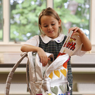 girl in school uniform with books and backpack