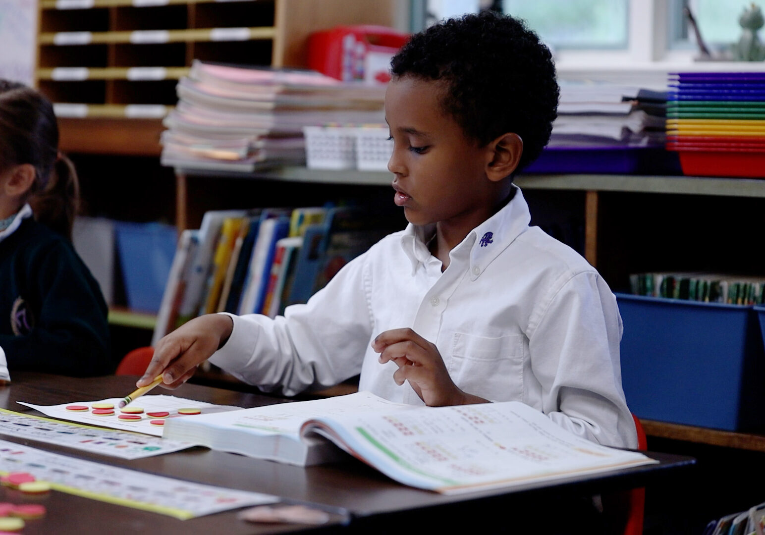 Kindergarten student using counting tokens during a classroom activity